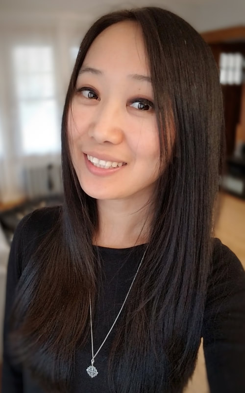 Picture of Suyao: smiling woman with brown eyes and long brown hair, wearing black shirt.